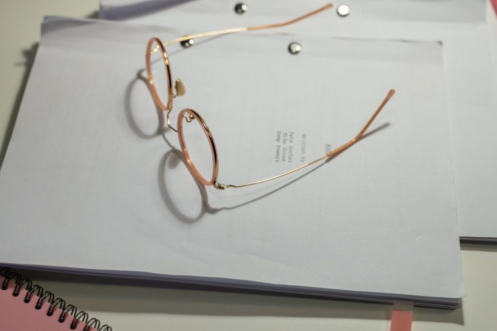 Close-up of eyeglasses resting on a stack of documents, emphasizing simplicity and focus.